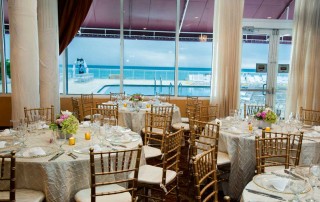 Tables set up in a reception room overlooking the pool and ocean.