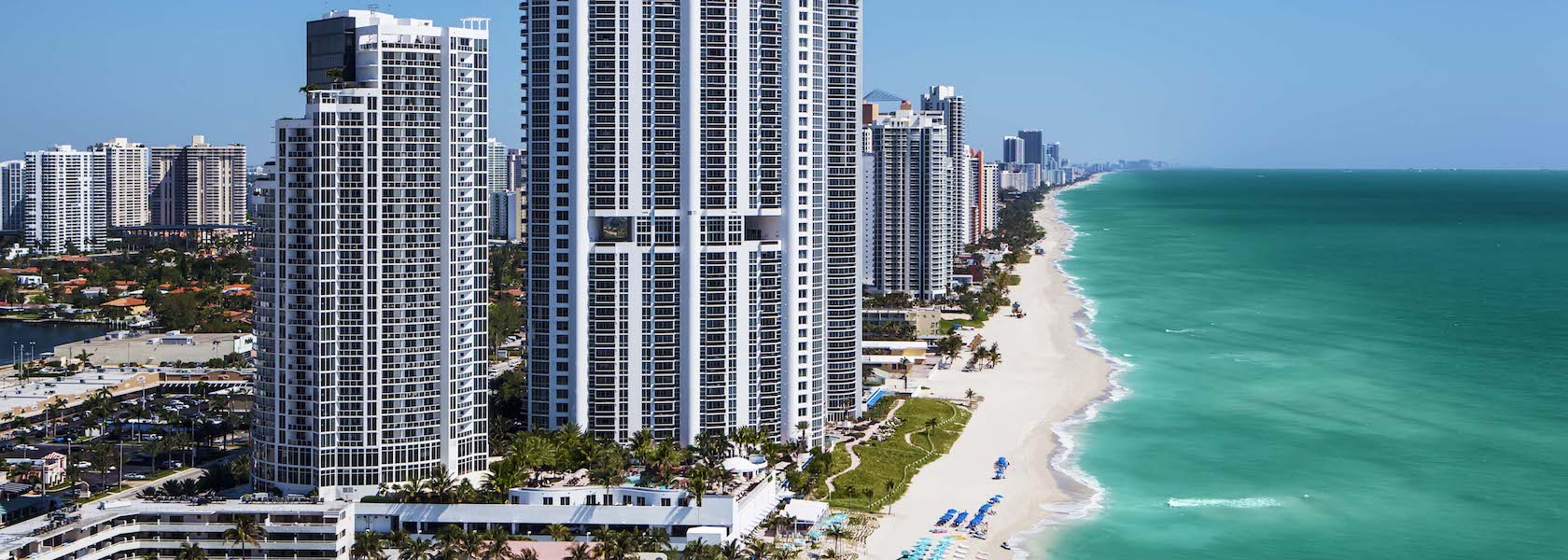 Trump International Beach Resort and hotels lining beach and aqua ocean.