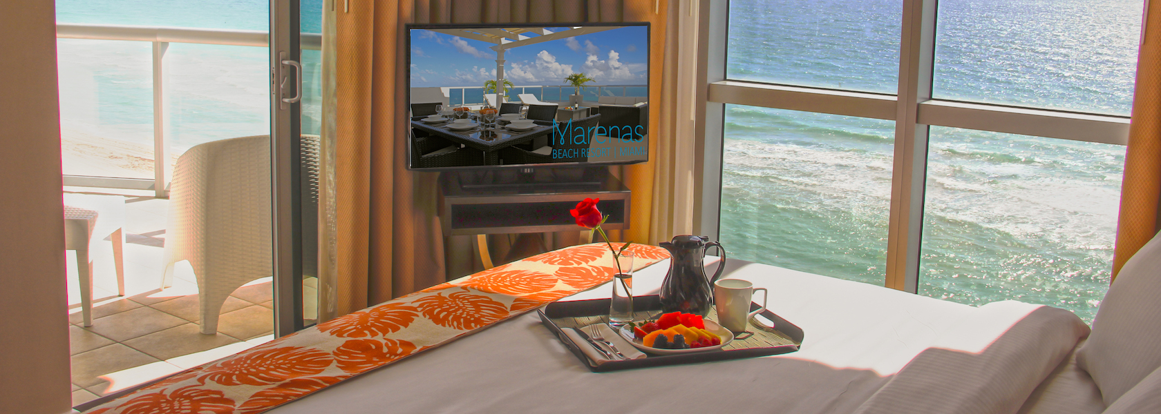 Breakfast tray on bed with ocean view in Marenas Beach Resort hotel room